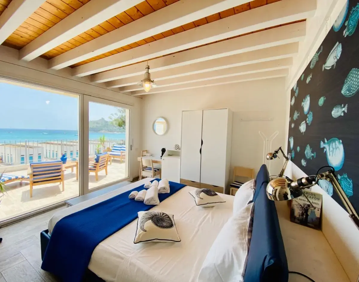 Camera con soffitto a travi di legno e grande finestra sul mare