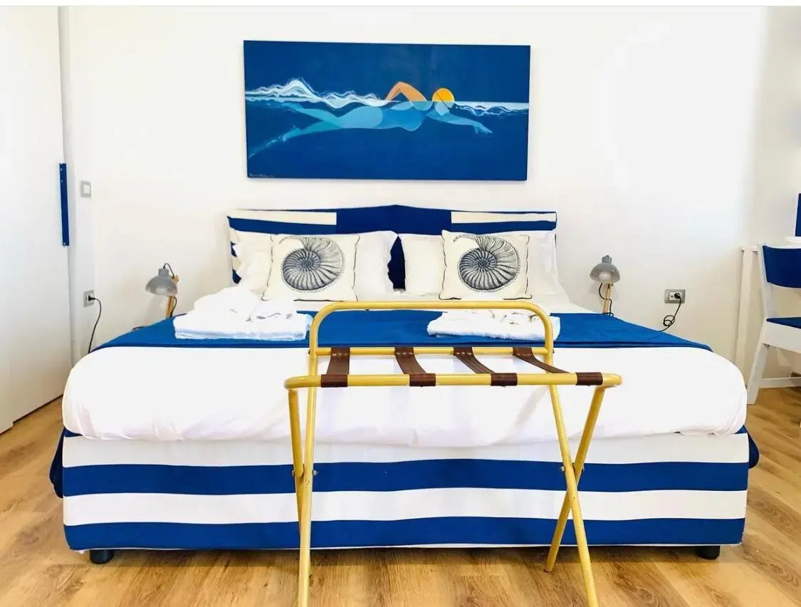 Letto matrimoniale con copriletto blu e bianco a righe e dipinto di un nuotatore