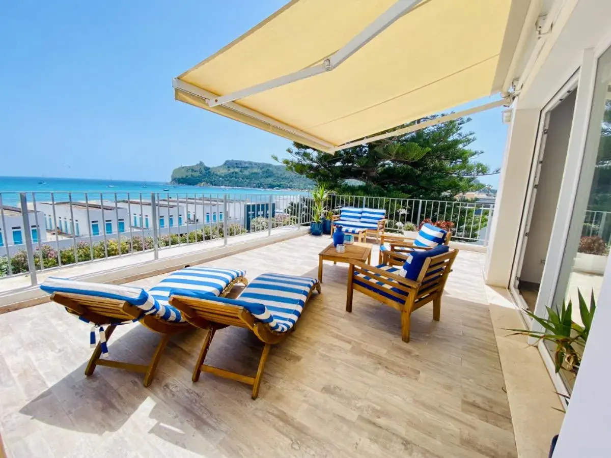 Terrazza con lettini e tavolino affacciata sul mare e sul promontorio